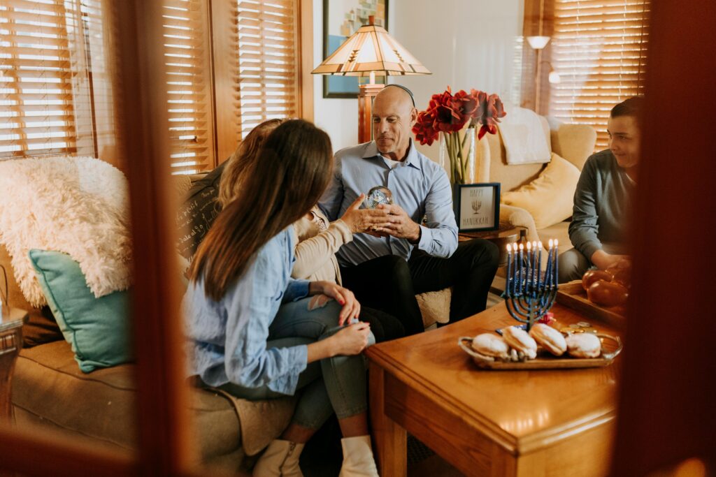 Warm indoor Hanukkah celebration with family, menorah lighting, and traditional foods.